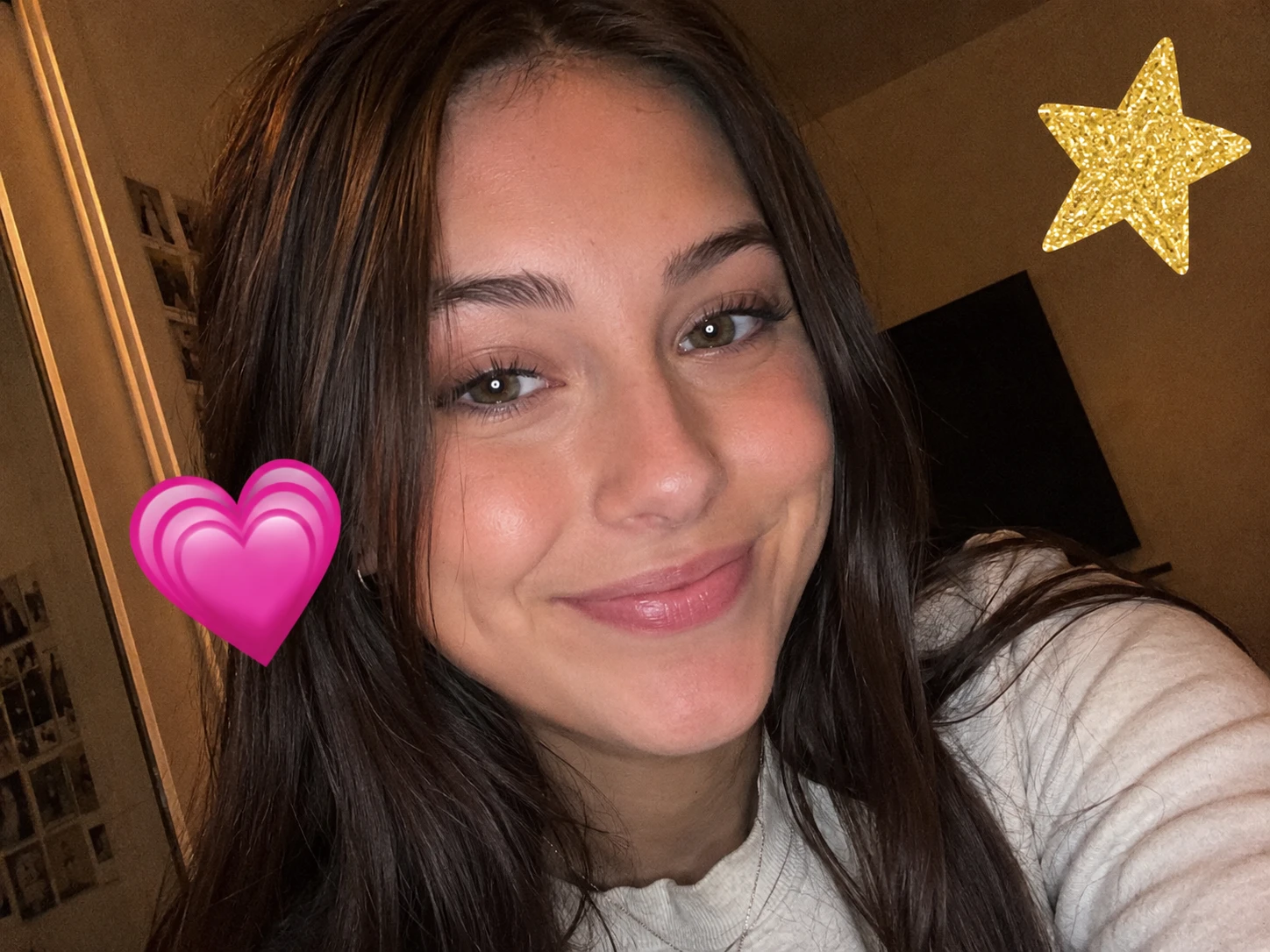 Selfie with a pink heart emoji near the cheek and a gold star emoji in the upper corner