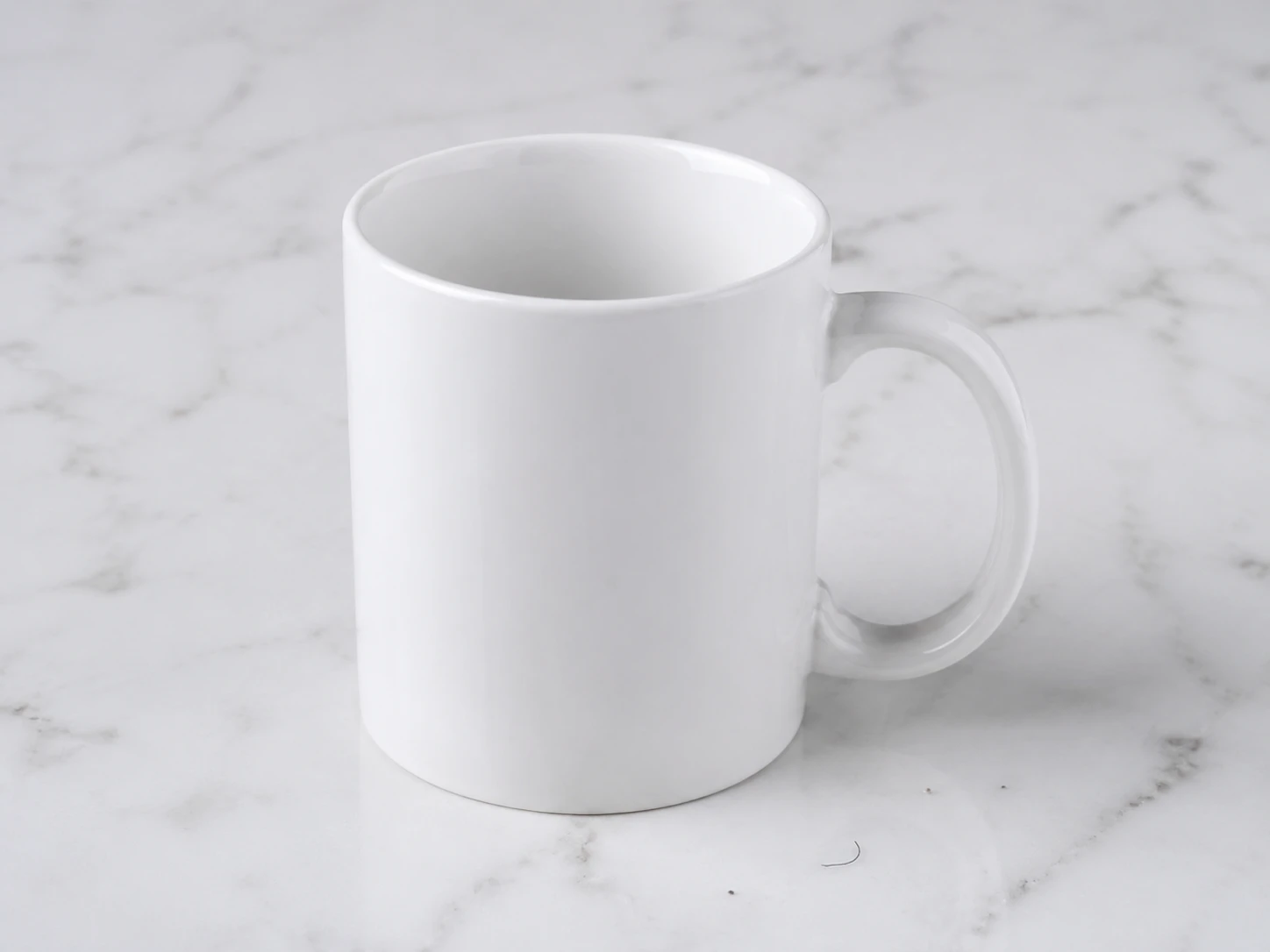 White ceramic mug product photo on marble with dust specks and lint visible nearby